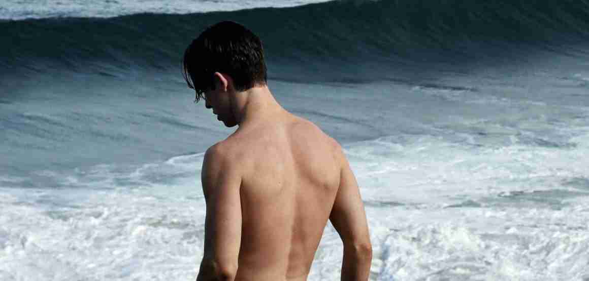 man-ontbloot-bovenlijf-strand-zee